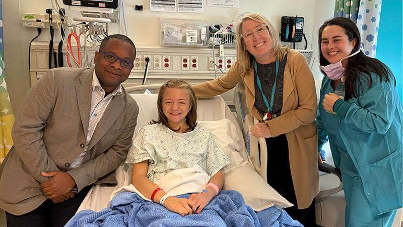 Dr. Andre Dick with transplant recipient, Mary, in hospital room with two other hospital staff.